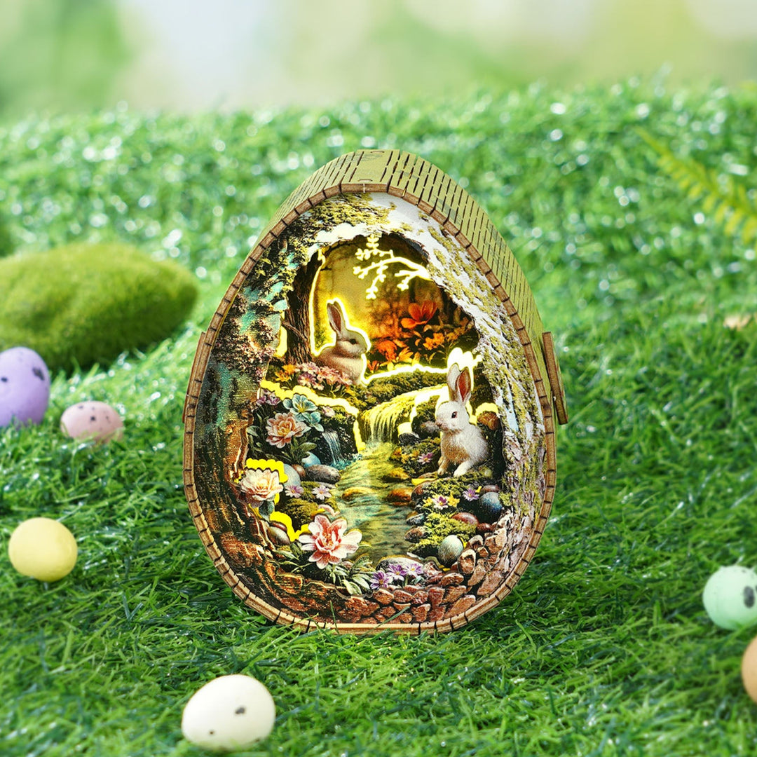 3D wooden puzzle night light featuring a serene scene of rabbits by a stream, surrounded by flowers and colorful eggs.
