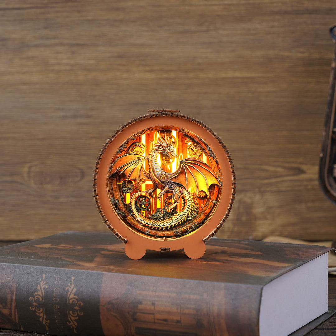 Mechanical dragon night light 3D wooden puzzle, glowing intricate design on a book with wooden background.