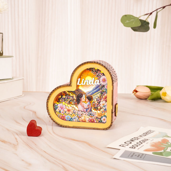 Heart-shaped decorative box featuring flowers and a mother-child illustration, with the name 'Linda' prominently displayed.