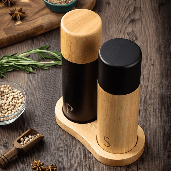 Sea salt and pepper grinder combo set in natural rubber wood on a wooden table with spices.