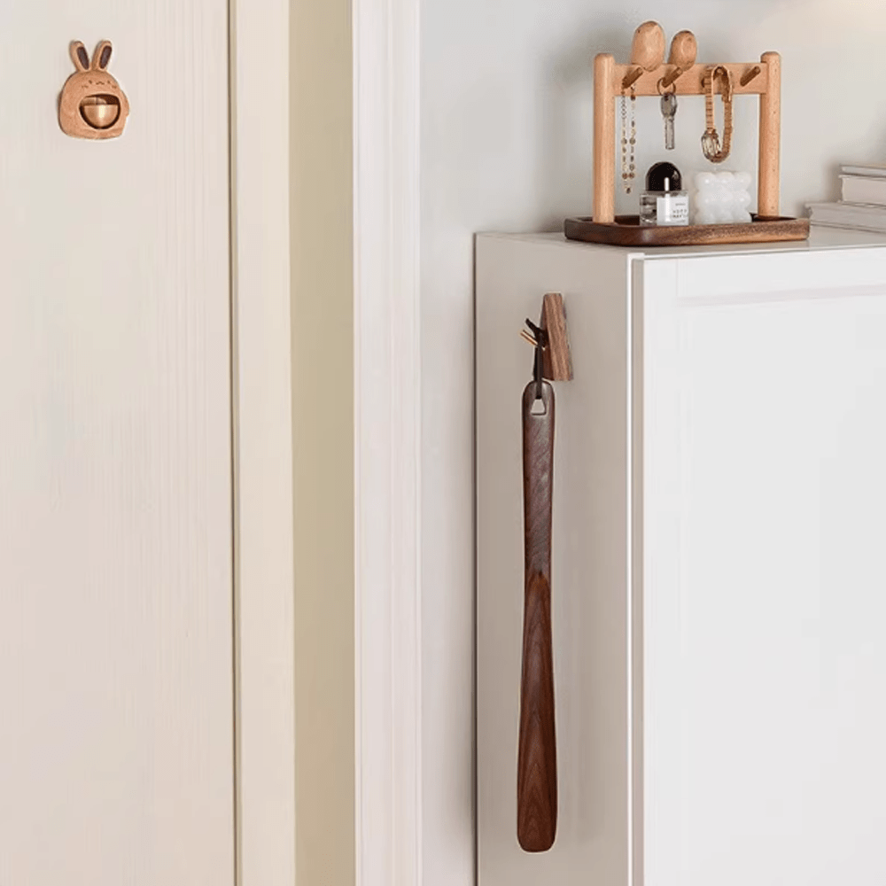Elegant walnut shoe horn hanging on a cabinet, showcasing natural wood tones and paired with stylish decor.