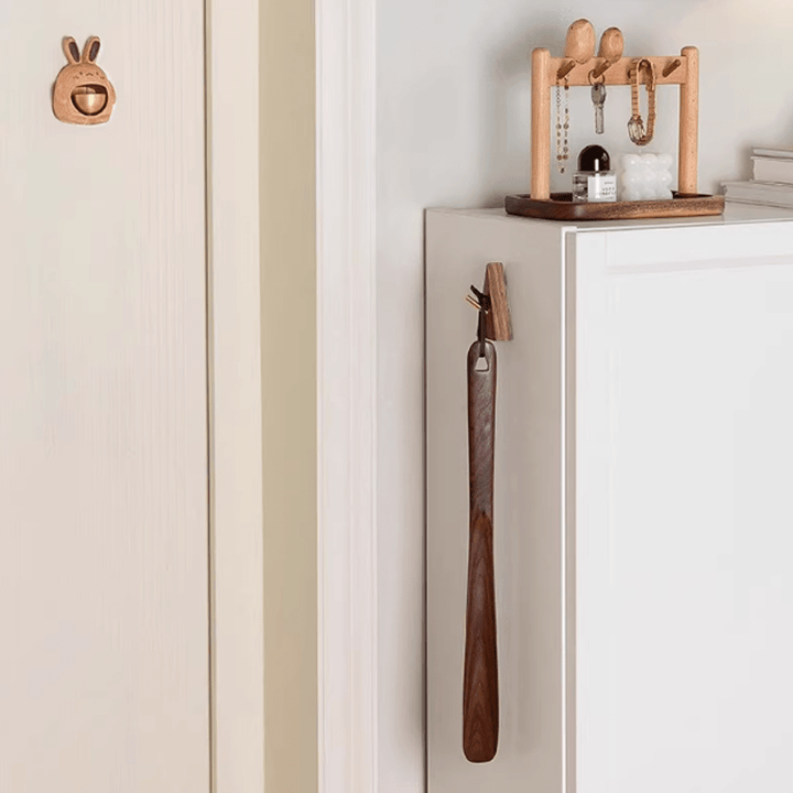 Elegant walnut shoe horn hanging on a cabinet, showcasing natural wood tones and paired with stylish decor.