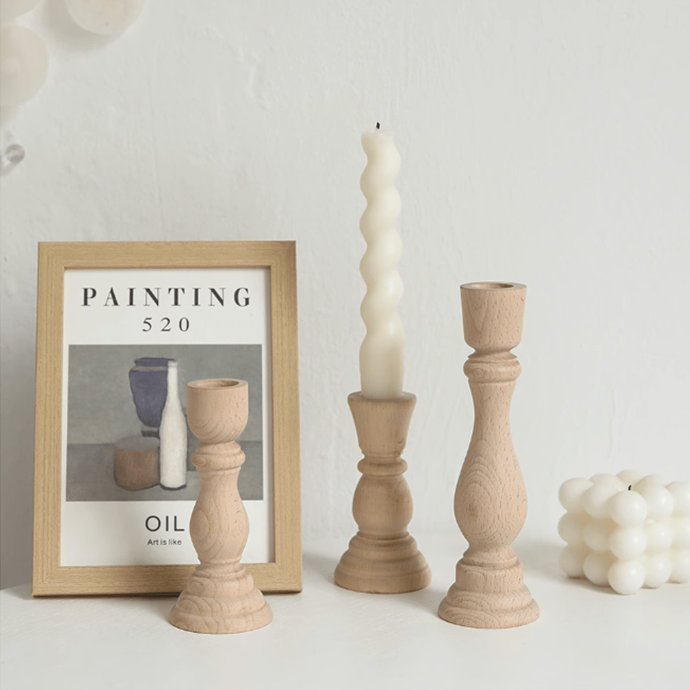 Nordic vintage wooden candle holders with a white candle and art framed painting in a cozy setting.