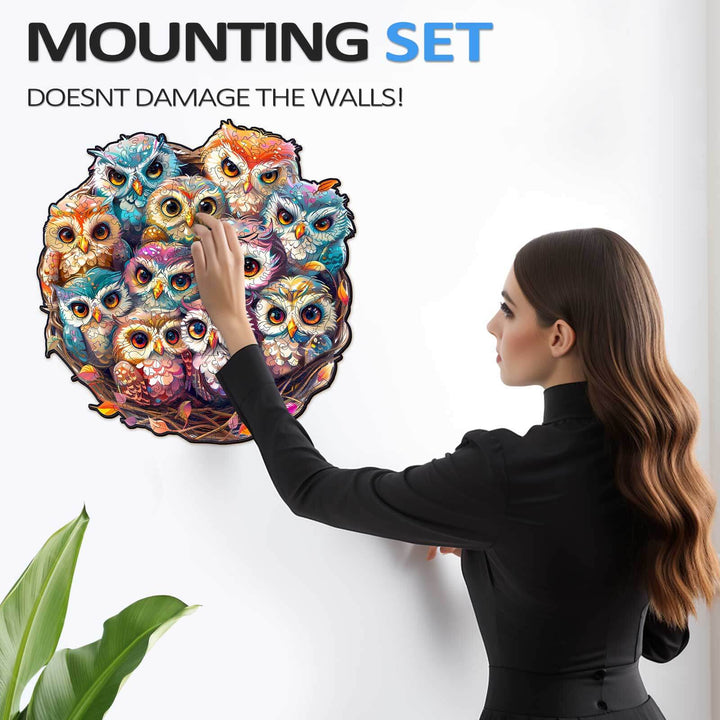 Woman using a wall mounting set to display a colorful owl puzzle without damaging walls.