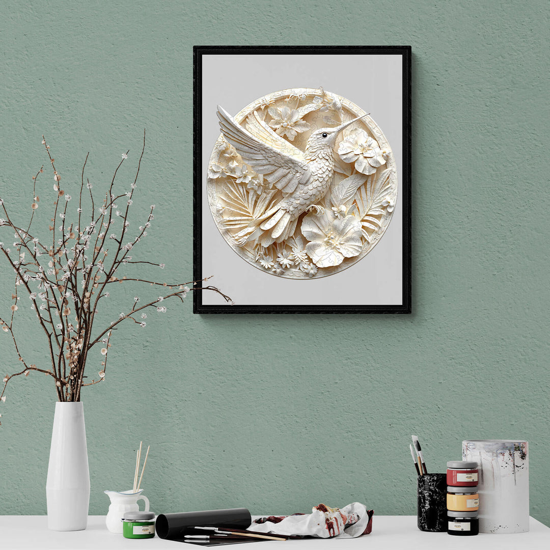 3D wall art of a hummingbird surrounded by flowers, framed in black, displayed on a green wall.