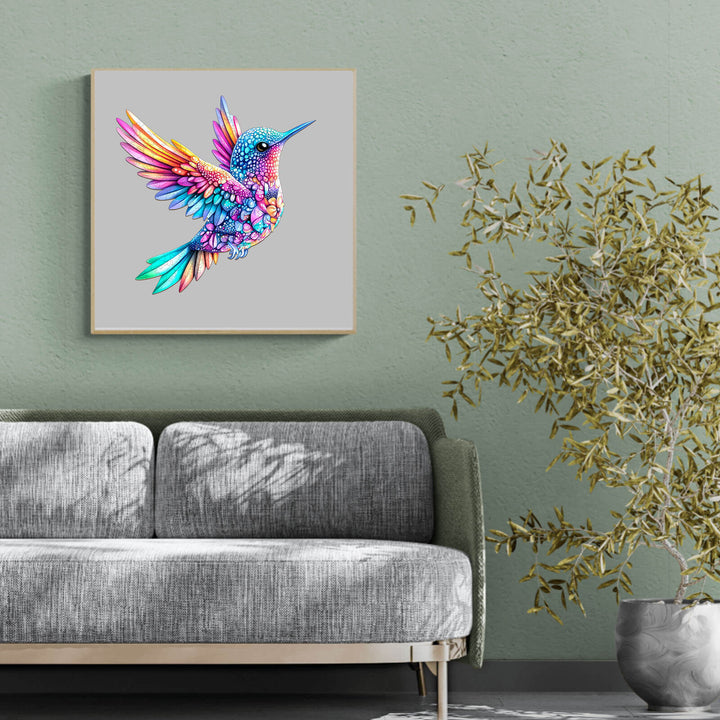Colorful Jewel hummingbird artwork displayed above a cozy gray couch, adding vibrant decor to the home.