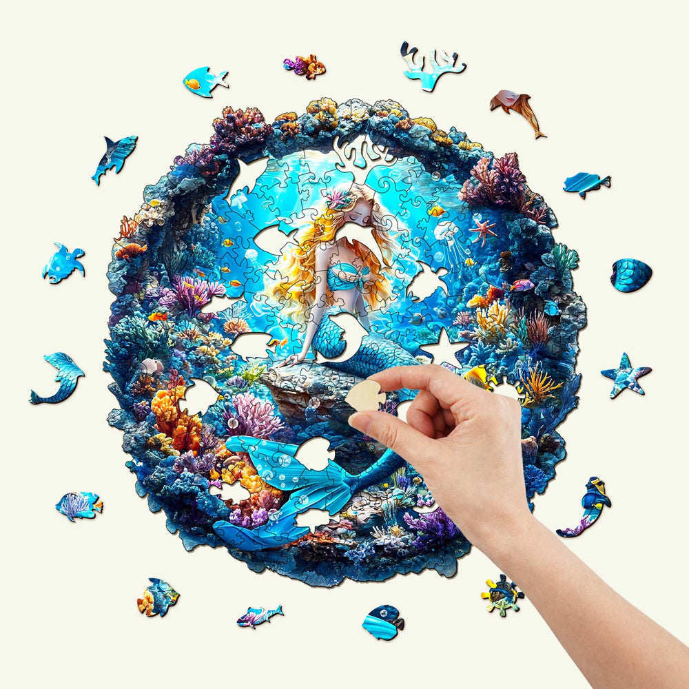 Hand placing a piece in a vibrant 3D Mermaid wooden jigsaw puzzle featuring colorful underwater scenery.