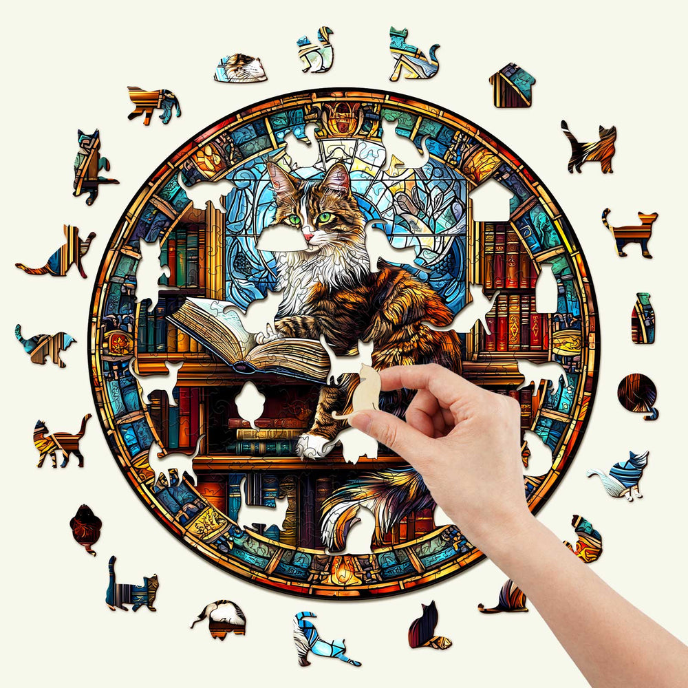 Person assembling The Maine Cat Library wooden jigsaw puzzle featuring a cat surrounded by books in a colorful design.