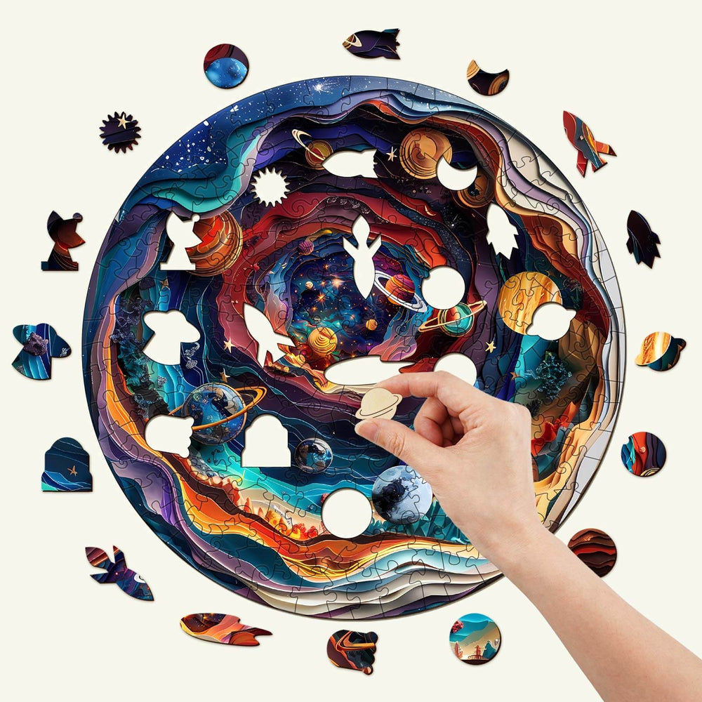 Hand placing a piece in the 3D Universe wooden jigsaw puzzle featuring vibrant cosmic designs and planets.