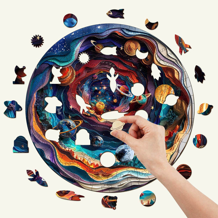 Hand placing a piece in the 3D Universe wooden jigsaw puzzle featuring vibrant cosmic designs and planets.
