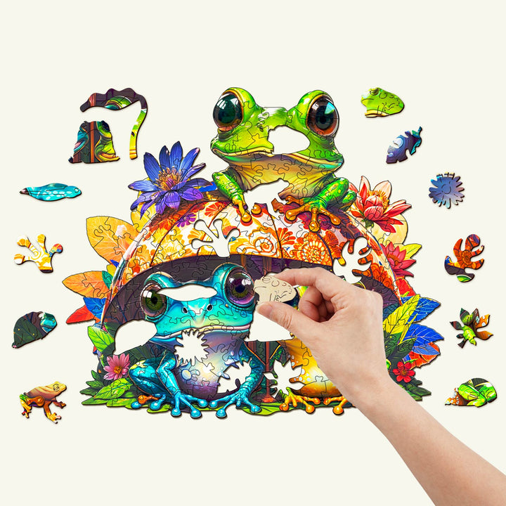 Colorful Frog Brothers wooden jigsaw puzzle with vibrant flowers and foliage, showcasing a hand placing a puzzle piece.
