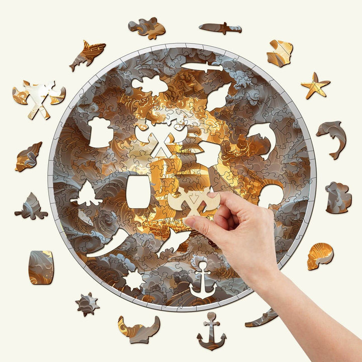 Hand placing a piece into the 3D Sailing-2 wooden jigsaw puzzle with marine-themed pieces surrounding it.