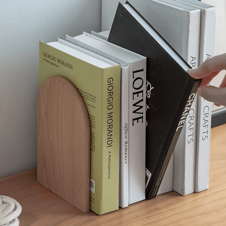 Wooden bookends elegantly supporting books with a modern design on a wooden surface.