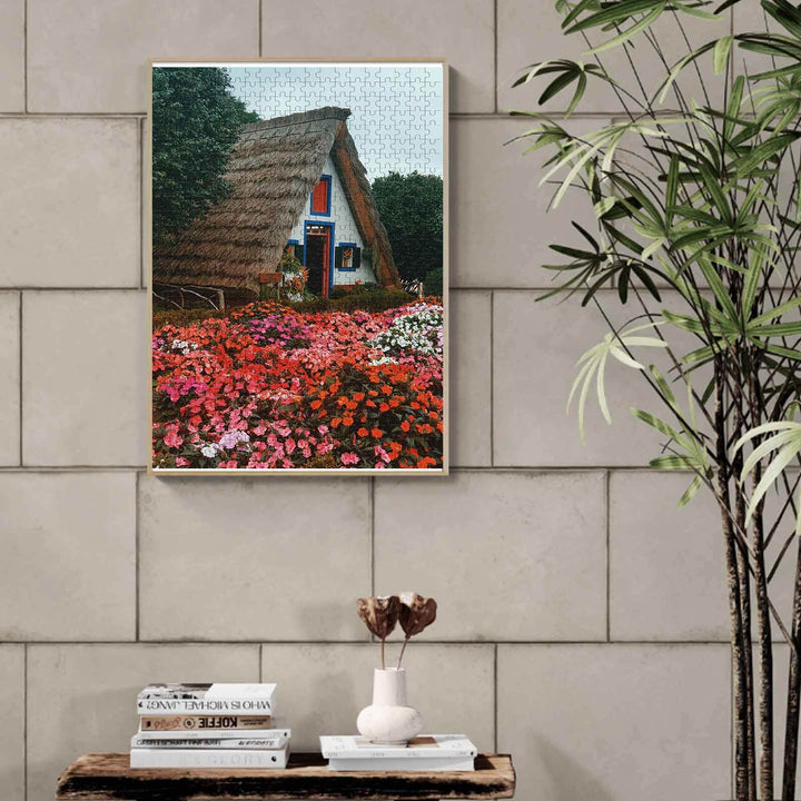 Flower House 500/1000 piece puzzle showcasing a thatched cottage surrounded by vibrant flowers, perfect for puzzle enthusiasts.