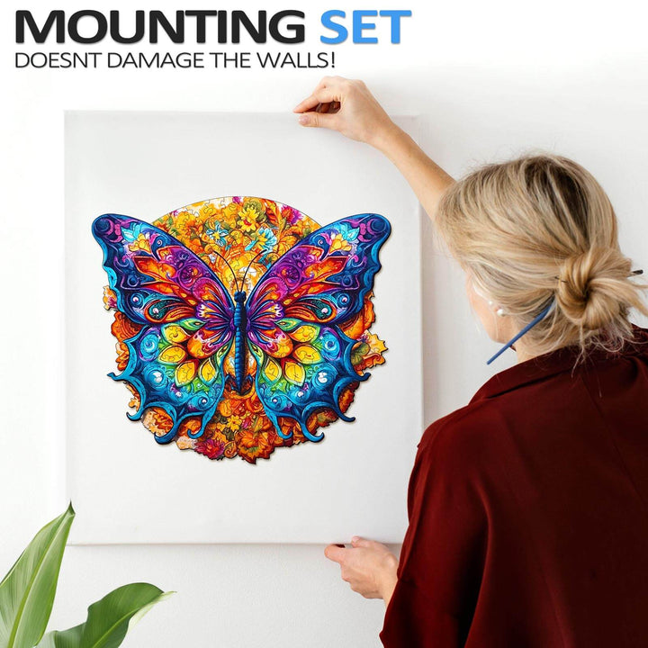 Person mounting a colorful butterfly art piece on the wall with a damage-free mounting set.
