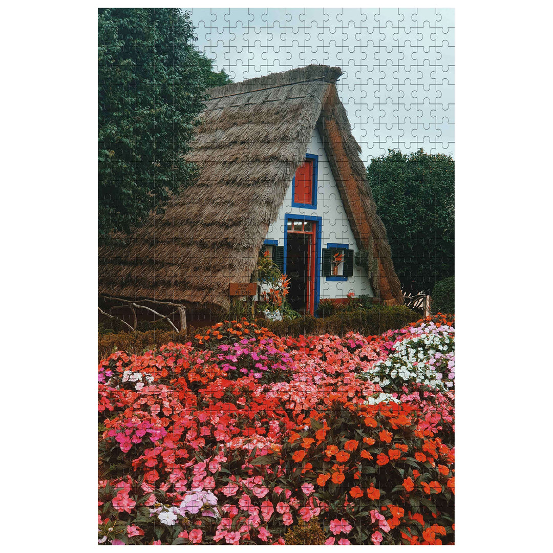 Flower House 500/1000 Piece Puzzle featuring a charming thatched cottage surrounded by vibrant flowers.