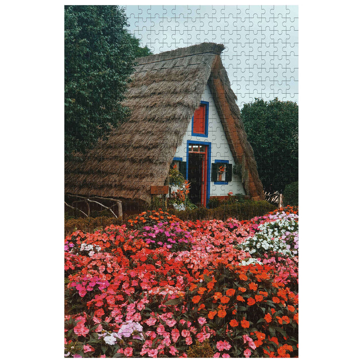 Flower House 500/1000 Piece Puzzle featuring a charming thatched cottage surrounded by vibrant flowers.