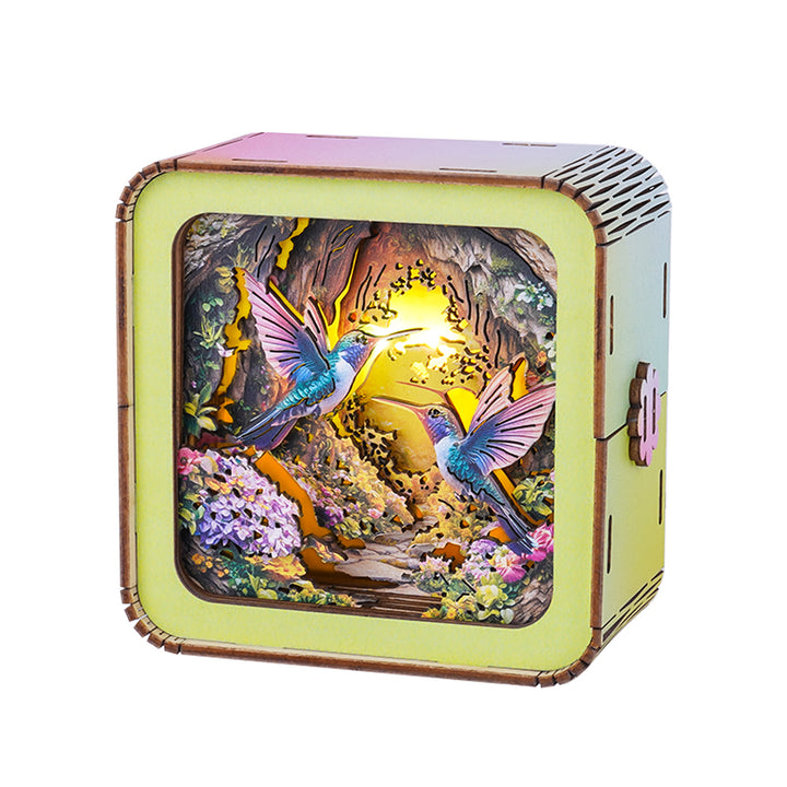 Colorful 3D wooden puzzle night light featuring hummingbirds and a cave scene with vibrant flowers.