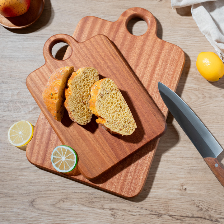 Two wooden cutting boards with sliced bread, lemon, and a knife on a rustic table, showcasing kitchen elegance.