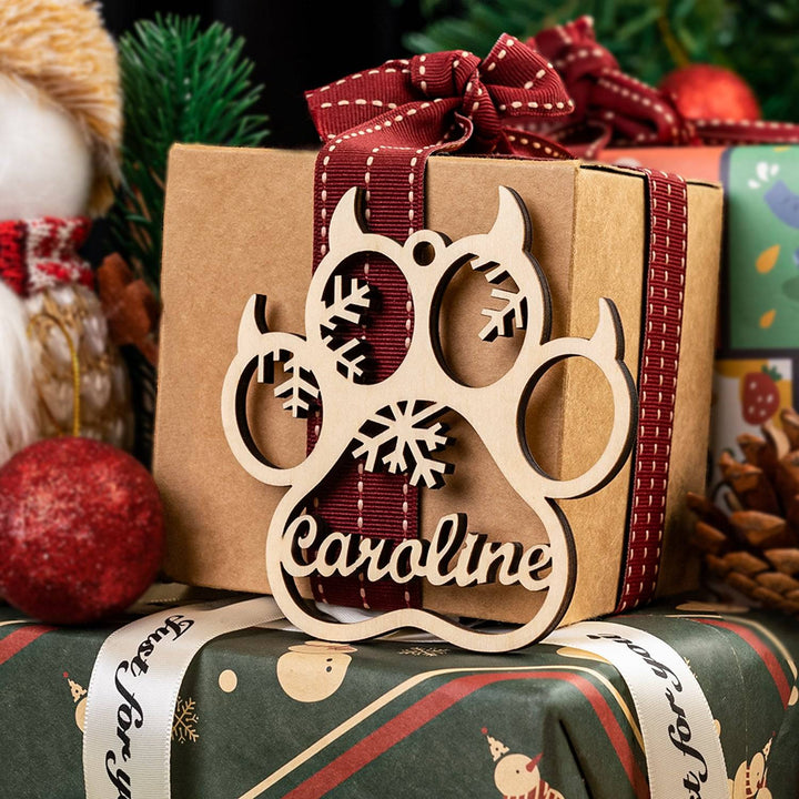 Personalized wooden cat/dog paw ornament with snowflakes and ribbon, perfect for holiday decor.