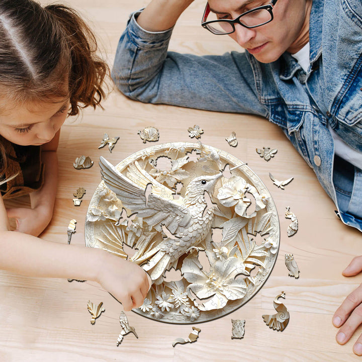 Child and adult working on a 3D Paper Hummingbird-2 wooden jigsaw puzzle on a wooden table.