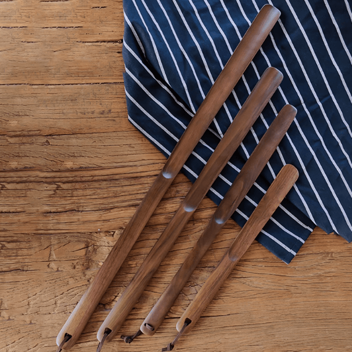 Set of four walnut shoe horns displayed on a striped fabric, showcasing natural elegance and ergonomic design.
