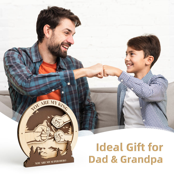Father and son sharing a fist bump beside a personalized wooden sign, an ideal gift for dad and grandpa.