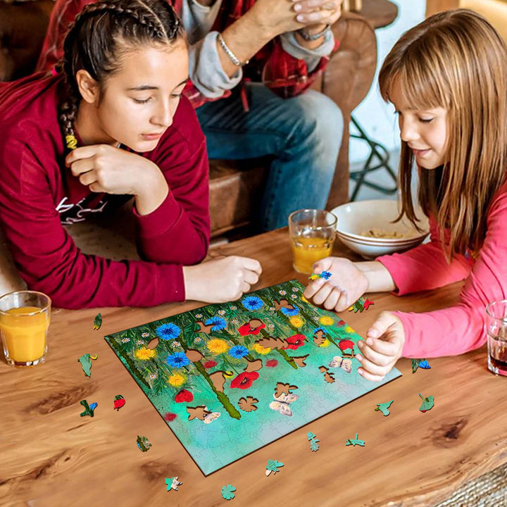Two girls enjoying a puzzle featuring a colorful Poppy Garden by Nicholas John VARDAXIS, surrounded by family and drinks.
