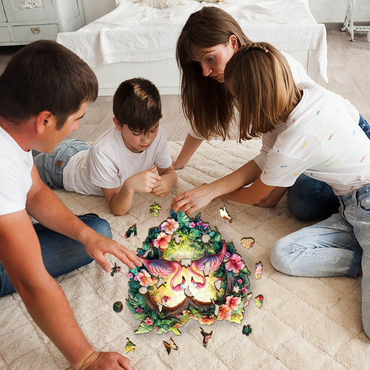 Family enjoying the Love Flamingos wooden jigsaw puzzle together on a cozy floor, focusing on pieces and bonding.