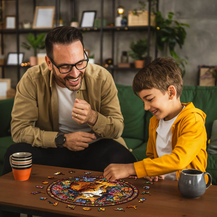 A father and son joyfully solving a Floral Feline wooden jigsaw puzzle together at home.