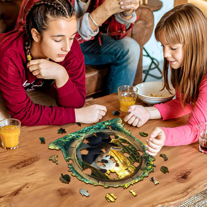 Two girls assembling a 3D Bamboo Grove Scholar Panda wooden jigsaw puzzle on a wooden table with drinks.