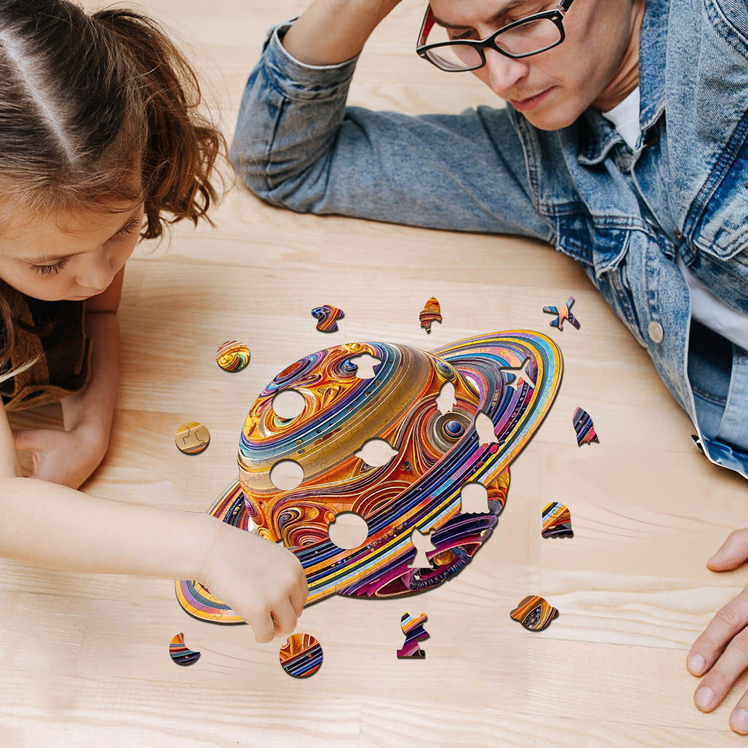 Child and adult assembling a colorful 3D Fantasy Saturn wooden jigsaw puzzle on a wooden table.