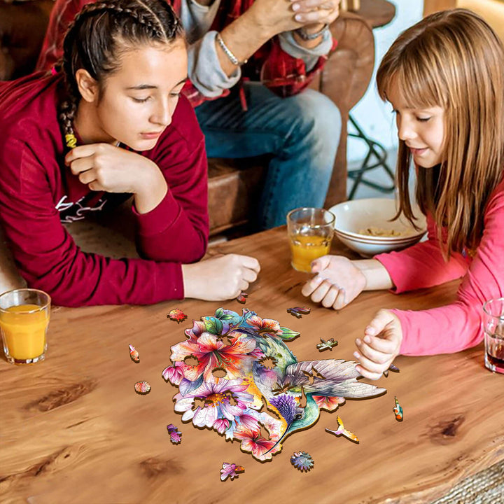 Two girls solving a Hummingbirds in Flowers jigsaw puzzle on a wooden table, enhancing focus and cognitive skills.