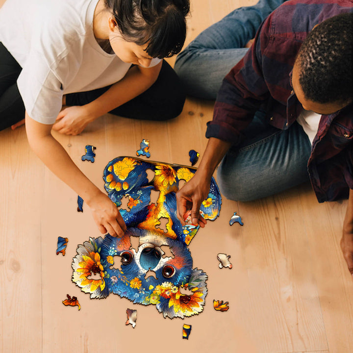 Two people assembling a colorful koala wooden jigsaw puzzle on the floor, enhancing focus and cognitive skills.