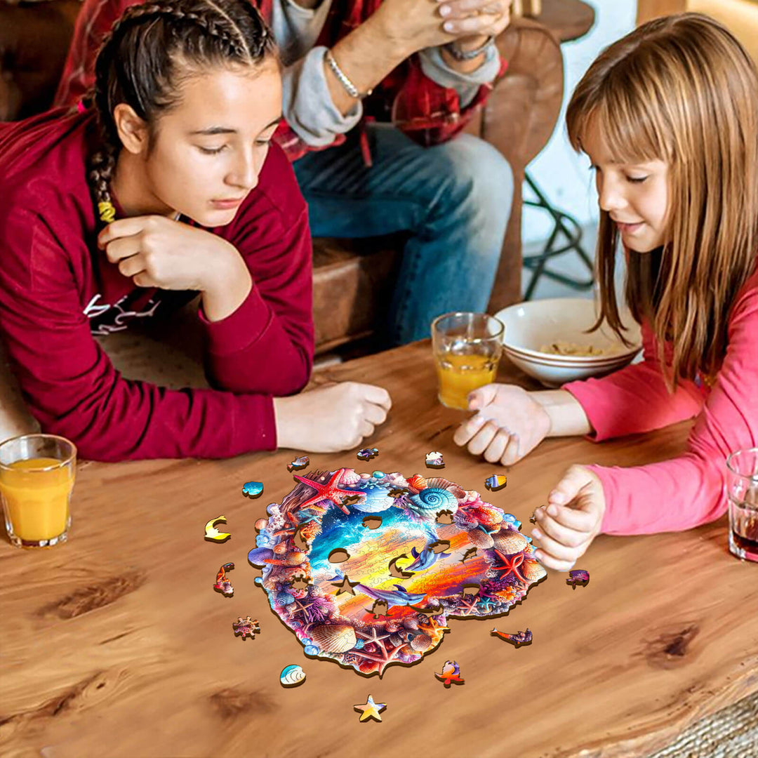Two girls focused on assembling a Coral and Dolphin wooden jigsaw puzzle on a wooden table, enhancing cognitive skills.