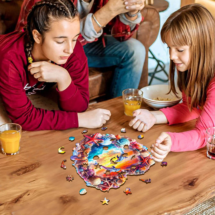 Two girls focused on assembling a Coral and Dolphin wooden jigsaw puzzle on a wooden table, enhancing cognitive skills.