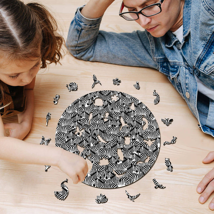A child and adult assembling a circular jigsaw puzzle on a wooden table, engaging in a fun puzzle-solving activity.