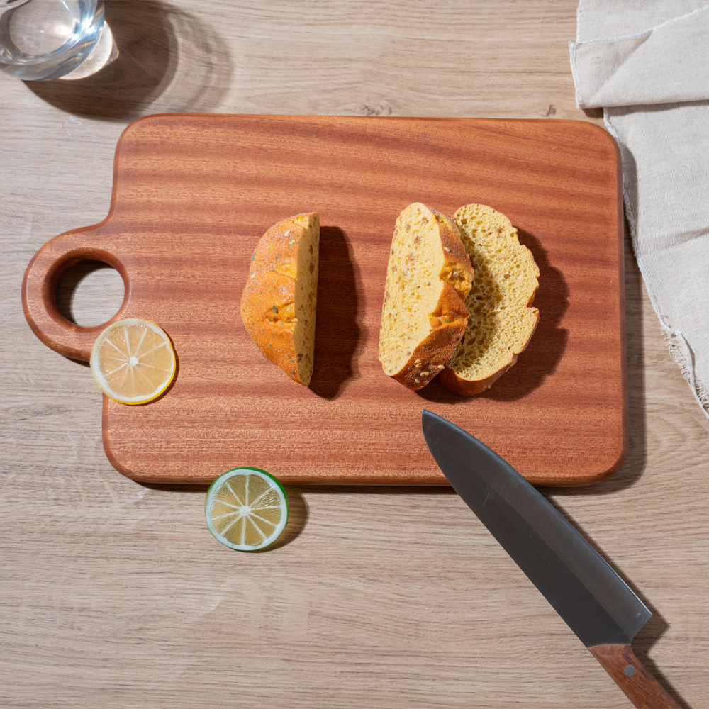 Polished wooden cutting board with sliced bread and lemon, perfect for kitchen use.