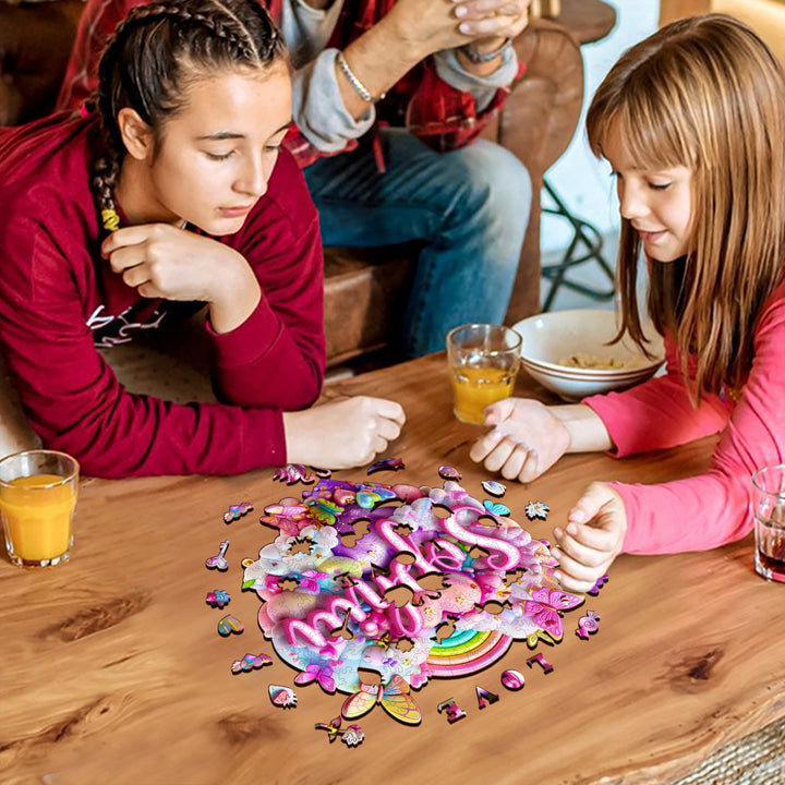 Two children enjoying playtime with a vibrant Rainbow Cloud custom name wooden jigsaw puzzle on a wooden table.