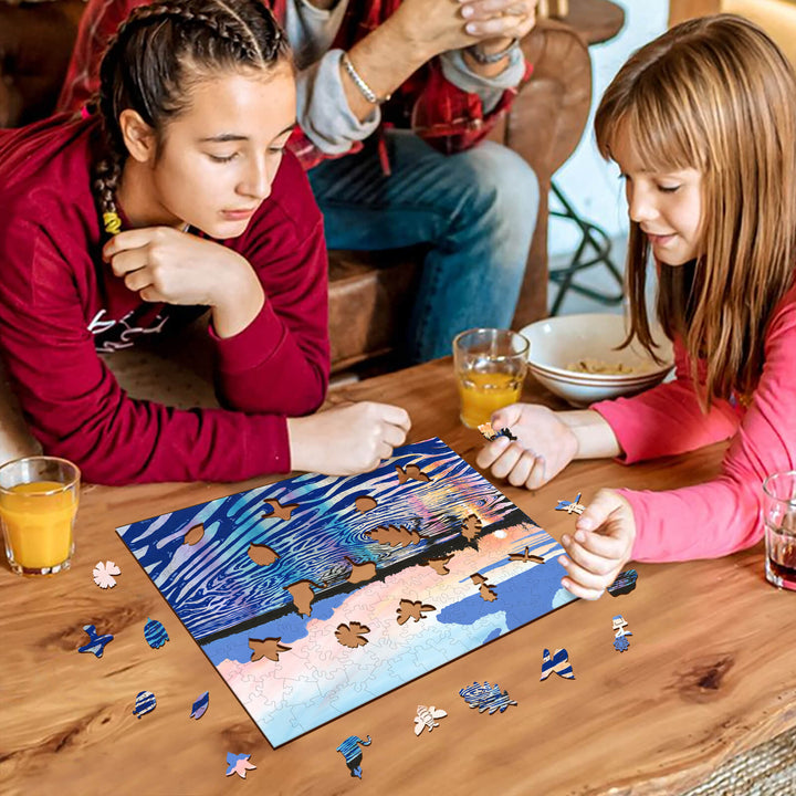 Two girls enjoying a puzzle featuring colorful artwork on a wooden table, with drinks and snacks around them.