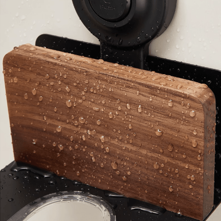 Suction cup hair dryer stand made of natural walnut, showcasing its water-resistant design with droplets on surface.