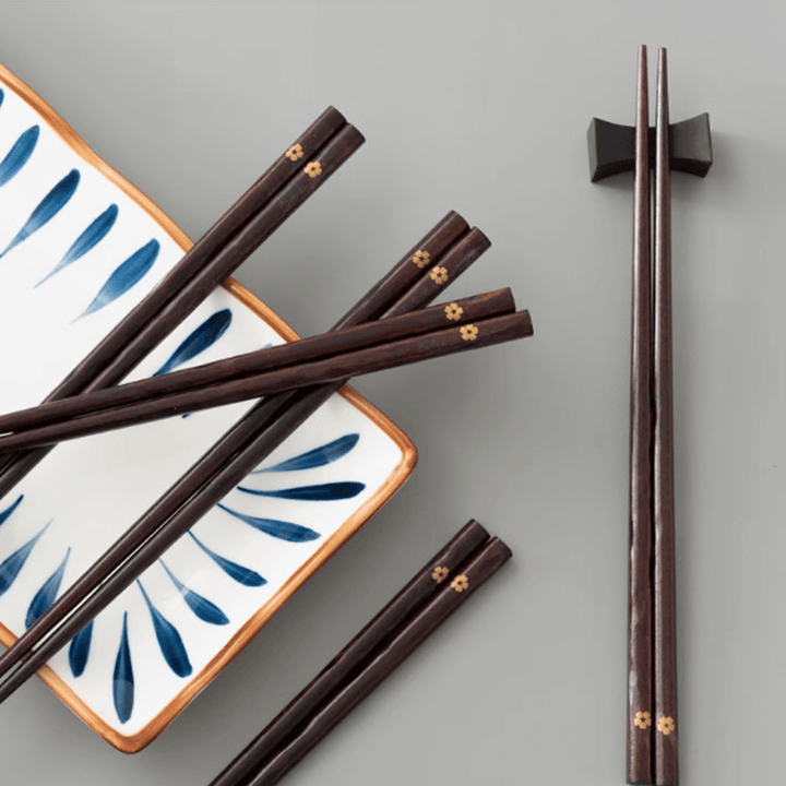 Non-slip Sakura wooden chopsticks set displayed on a decorative dish, showcasing elegant design and cherry blossom tips.