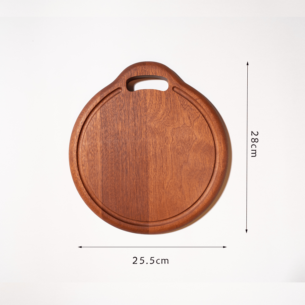 Round multi-functional cutting board made of ebony, featuring a built-in juice groove and a convenient handle.