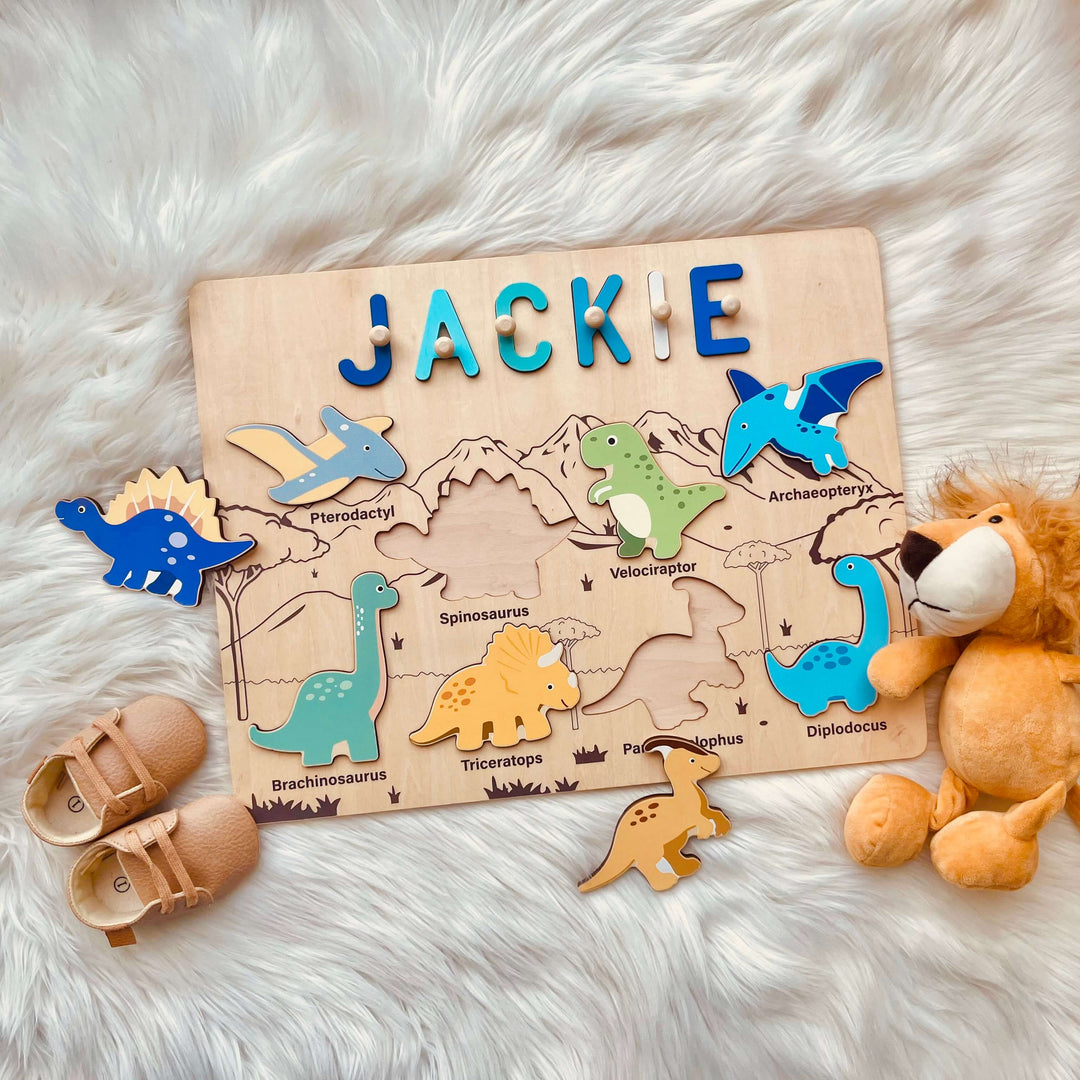 Personalized dinosaur name puzzle with colorful wooden dinosaur pieces and the name 'Jackie' on a soft surface.