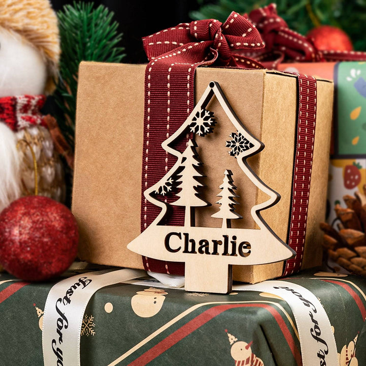 Personalized wooden Christmas tree ornament with the name Charlie, beautifully tied to a gift box.