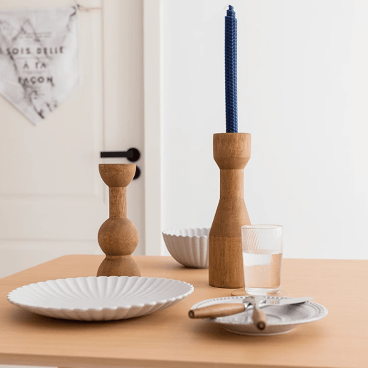 American retro wooden candle holders with blue candles, white plates, and glass on a wooden table.