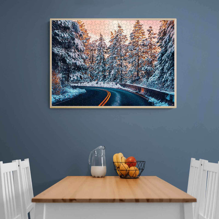 Snow Country Highway puzzle displayed on wall, showcasing a snowy road surrounded by evergreen trees.