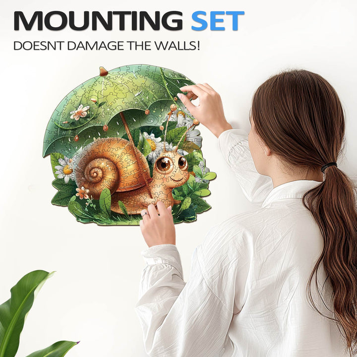 Person mounting Leisurely Snail Wooden Jigsaw Puzzle with a protective umbrella, showcasing wall-friendly design.