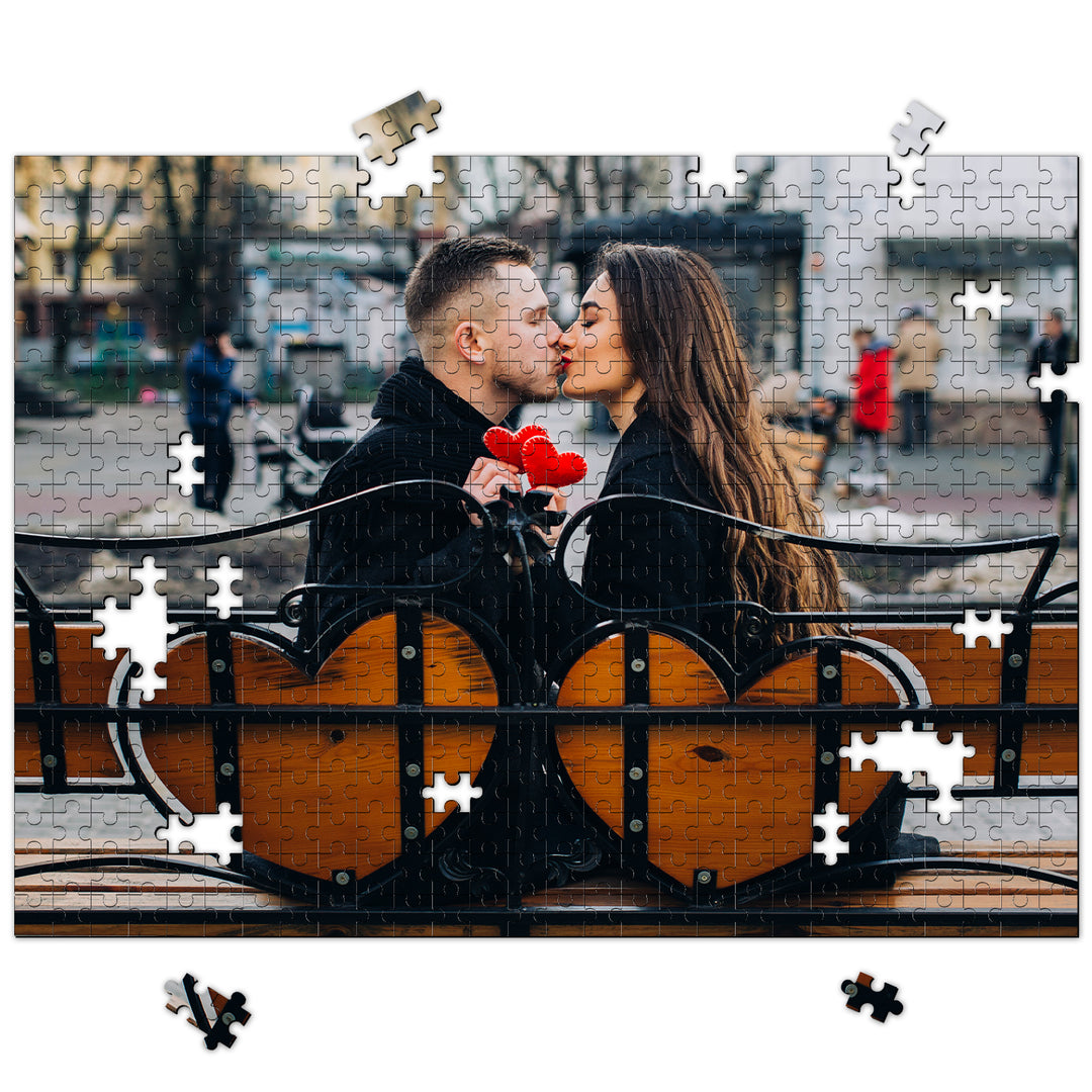 Couple sharing a kiss while assembling a heart-themed photo puzzle, symbolizing love and togetherness.