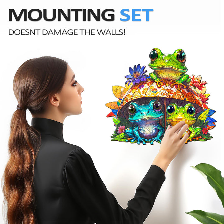 Woman using a mounting set to display colorful frog wall art without damaging the walls.
